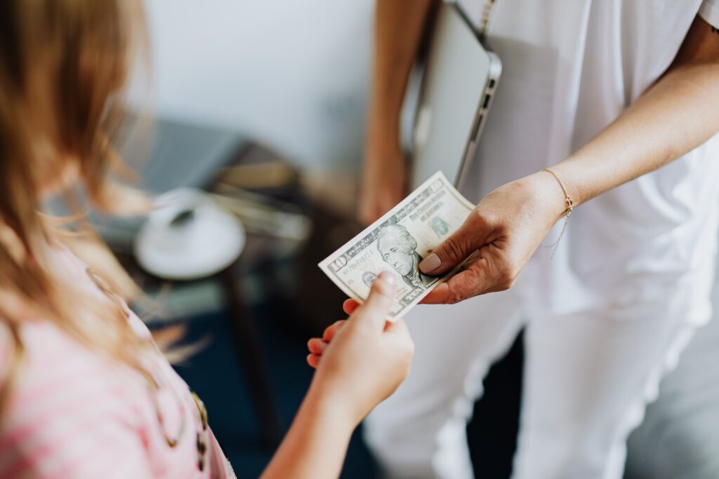 Person handing a $100 bill to another person during a cash payment transaction.